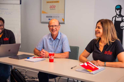 Trois personnes souriantes assises autour d'une table lors d'un atelier ADIE.